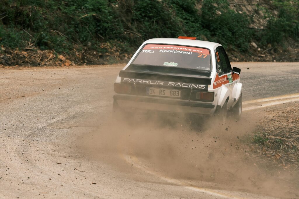 A rally car skidding on a curved road, showing reduced friction and the physics of centripetal force during sharp turns.