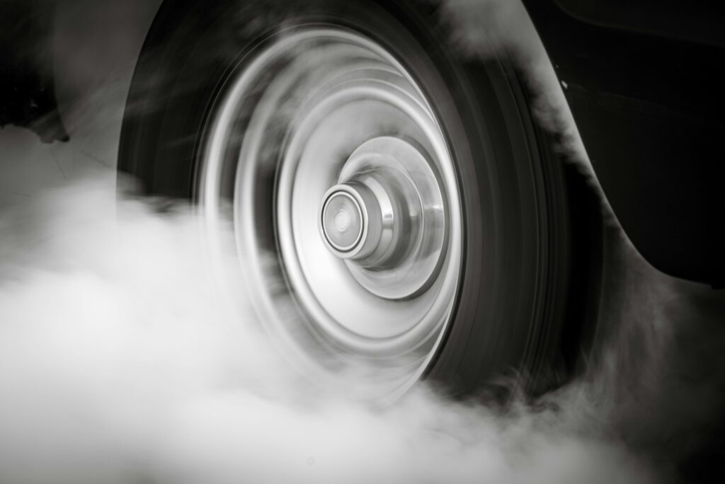 A spinning tire producing smoke, illustrating friction, acceleration, and the transfer of force between the tire and the road.